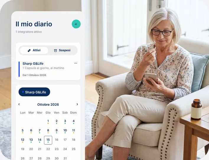 Una donna seduta in poltrona usa lo smartphone; accanto, il diario di IntegraMente con il calendario delle assunzioni del mese.